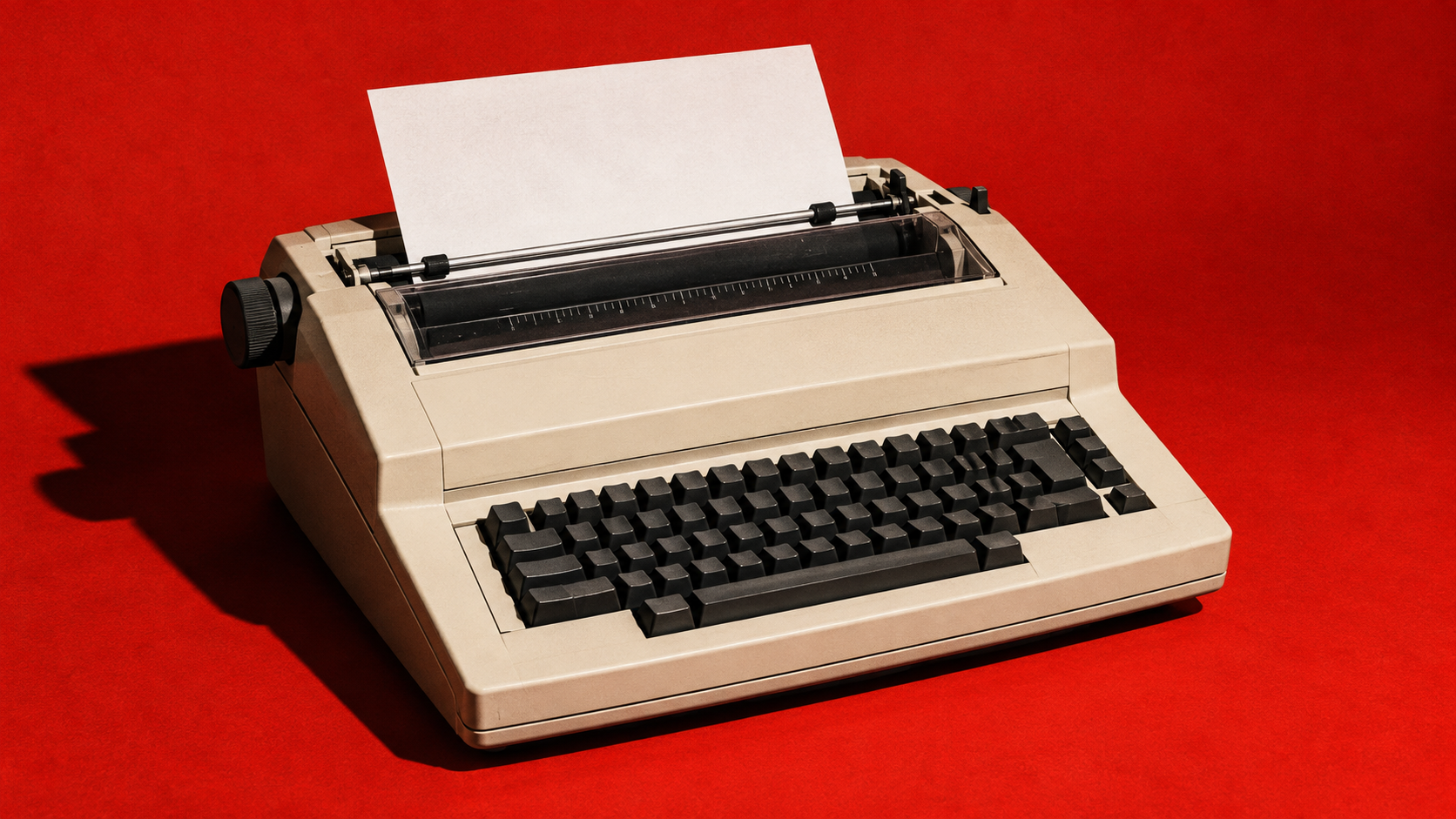 Cream colored electric typewriter against a red backdrop